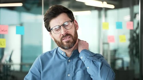 Man Rubbing Aching Neck in Office Setting
