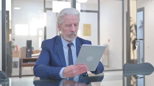 Senior Man Using Tablet in Office Setting