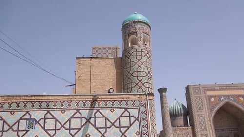 tall minaret with bright blue dome in Registan square in Samarkand, Uzbekistan along the historic Si