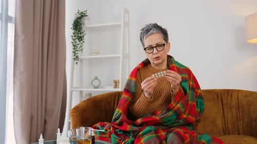 Woman with Blanket Taking Medication at Home