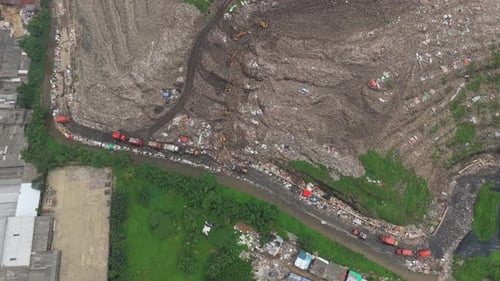 Aerial view of a huge landfill with garbage trucks dumping waste