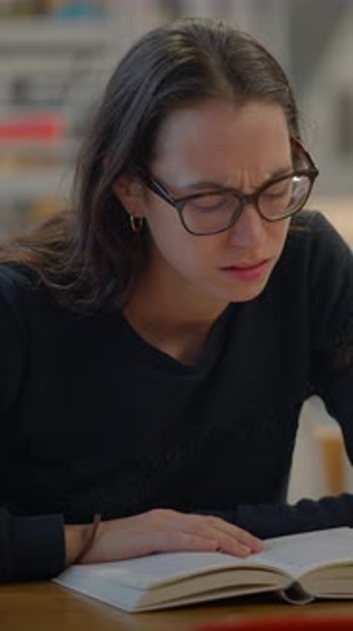 A Focused Student is Studying Diligently in a Quiet Library Immersed in Their Work