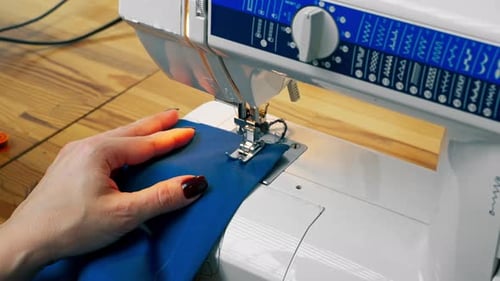 Closeup in a Sewing Workshop on a Machine the Seamstress Master Makes Cut on a Blue Fabric