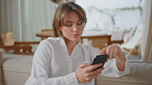 Woman Using Mobile Phone on Couch Indoors