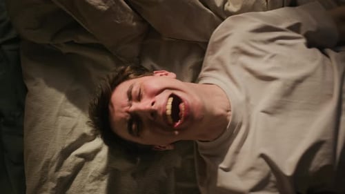 Jeune homme criant fort de désespoir sur le lit la nuit