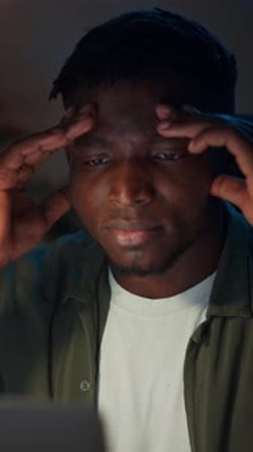 Man Rubs Temples While Looking at Computer Screen