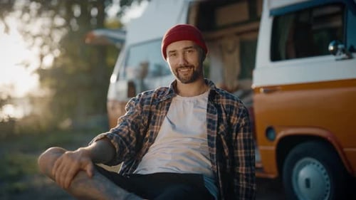 Smiling Man Sits Beside Campers During Golden Hour