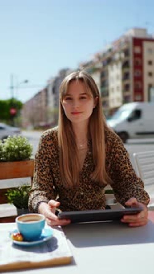 Blonde Woman Closing Digital Tablet While Drinking Coffee Enjoying Croissant at Sunlit Outdoor Cafe