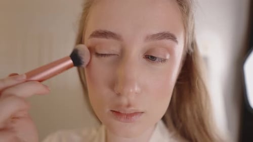 Woman Applying Makeup with Brush in Bathroom