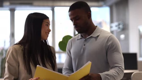 Coworkers discussing documents in modern office
