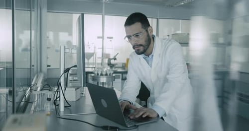 Scientist Works on Laptop in Modern Laboratory