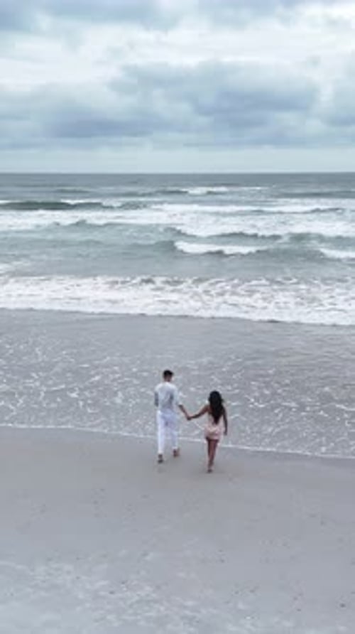 Romantic Young Couple Walking Hand in Hand on Beach