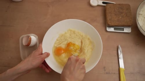 Woman Hands Cracking an Egg Into a Bowl and Whisking Before Folding in Flour to Make Homemade Dough