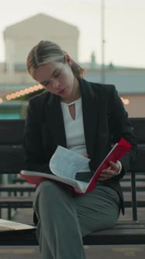 Focused Woman Reviews Documents on Park Bench