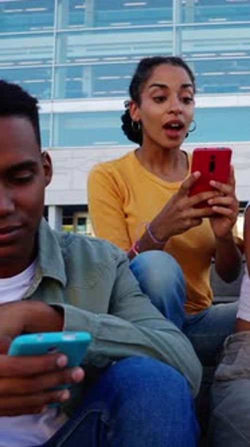 Happy Diverse Group of Young College Friends Having Fun Using Mobile Phones