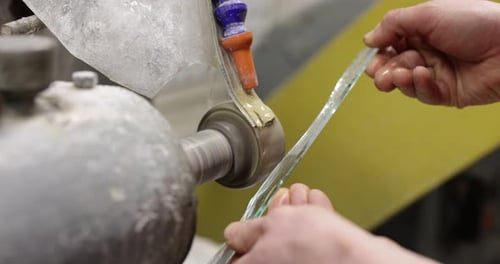 Worker grinding piece of glass in workshop, closeup