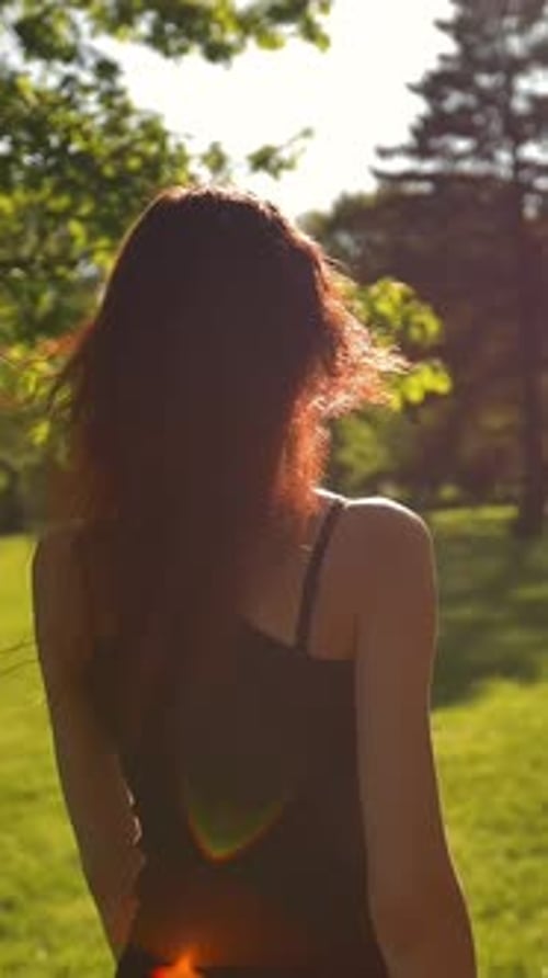 Vertical of Young Sexy Ginger Lady in Park Turns Around and Looking Very Cheerful and Happy Sunset