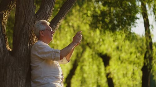 Senior Man Using Phone in Scenic Park