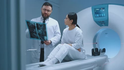 Doctor Reviews Scan with Patient by CT Scanner