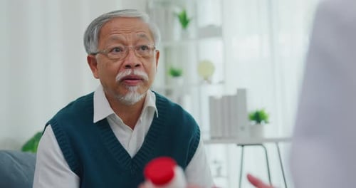Senior Man Talking with Doctor Holding Pill Bottle