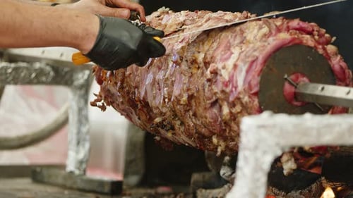 Chef Slicing Doner Kebab Meat with Long Knife