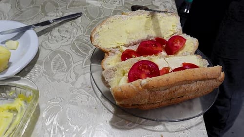 Hands Adding Sauce to a Sandwich on a Plate