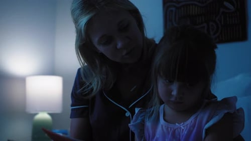 Mother and Child Reading Book at Night