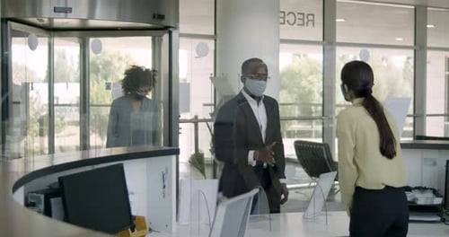 Business people arriving in corporate office lobby wearing protective face mask