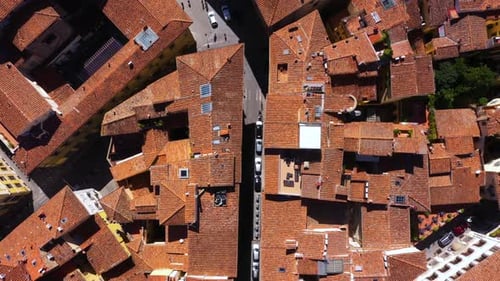 Top down view flying above roofs, roads and city on a sunny day in Florence in Italy in 4k.