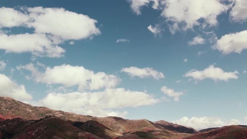 Aerial drone shot panning down from clouds to mountains in Salt Lake City with fall-colored leaves a
