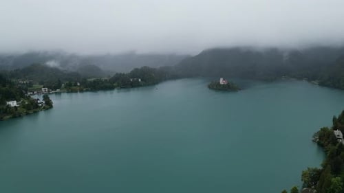 Lake Bled Slovenia drone aerial view misty mountains in background