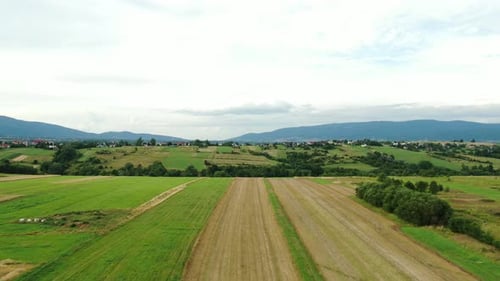 Toma aérea de campos con montañas en el fondo, día nublado.