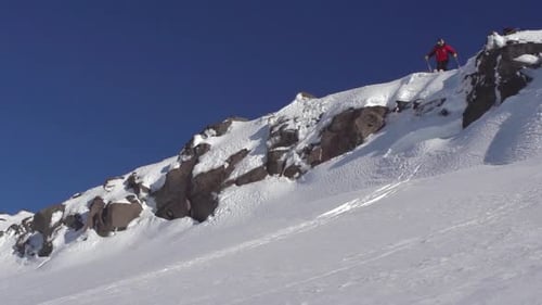 Extremer Freeride-Skifahrer, der langsam von einer Klippe springt und einen Grabtrick in der Luft ausführt