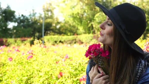 Woman Holds Flower Blows Kiss In Garden