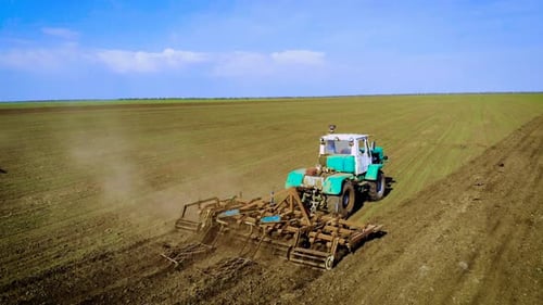 Farmer on Large Tractor Cultivates Field and Prepares Soil for Sowing Crops
