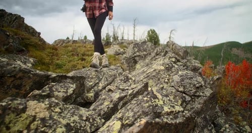 Hiker Walking Up Rocky Mountain During Cloudy Autumn Day