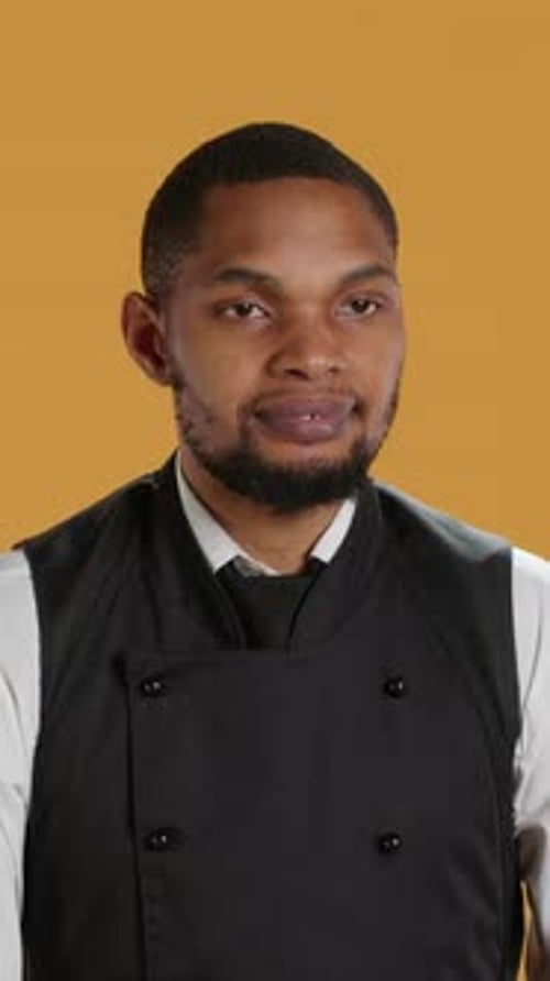 Vertical Video Waiter Flexing His Muscles and Showing His Strength in Studio