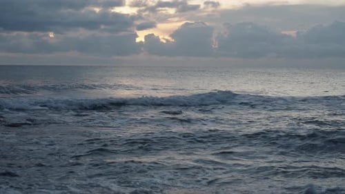 Stormy clouds and the sunset behind them. Turbulent waters with deep blue hues.