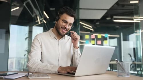 Man Working at Laptop With Headset in Office