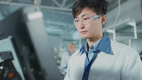 In einer High-Tech-Fabrik verwendet ein asiatischer Ingenieur einen Computer zur Programmierung von Elektronisch Pick-and-Place-Maschinen