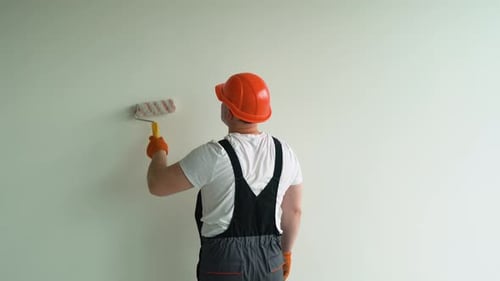 Man Painting a Wall with a Paint Roller