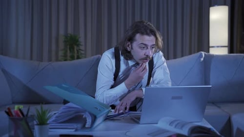 Thoughtful Man Works at Laptop Late at Night