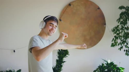 Energetic Young Man Dancing with Headphones Indoors