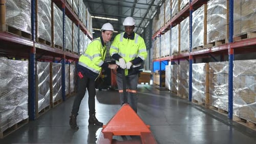 A worker in an auto parts warehouse assists a friend by instructing them to use a work cart