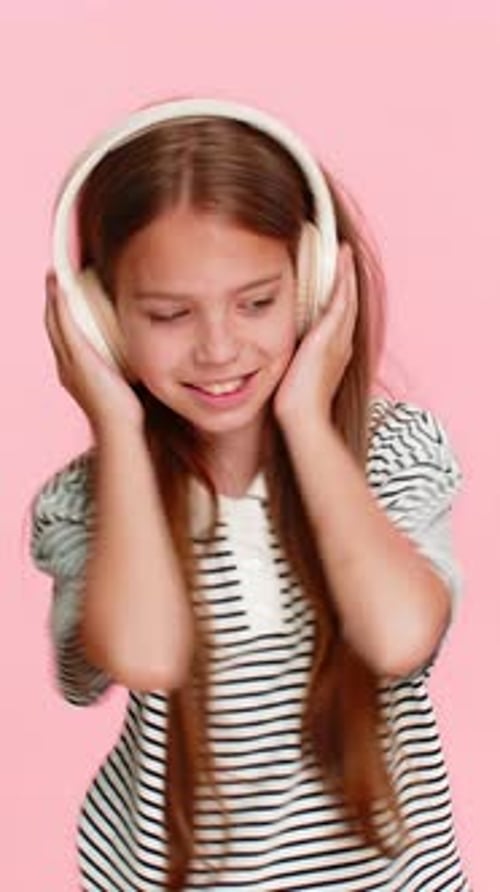 Girl Dancing to Music with Headphones on Pink Background