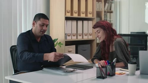 Office Colleagues Discussing Documents at Desk