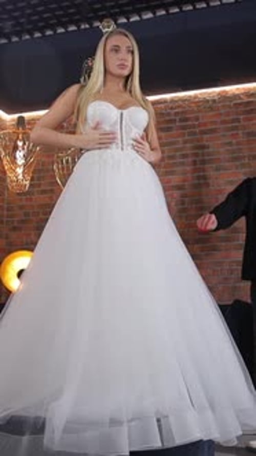 Vídeo vertical de noiva loira alta e elegante experimentando um vestido de noiva em uma boutique de noivas
