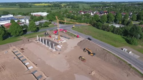 A drone flies over a large construction site on which a huge production hall is being built.