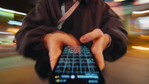 Woman Using Phone on City Street at Night