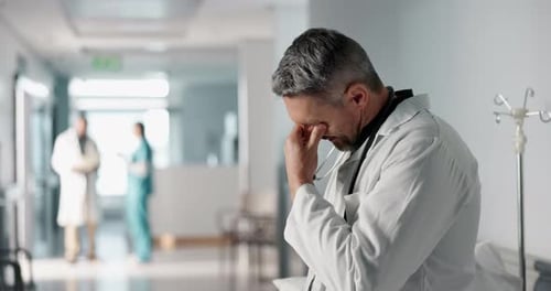 Stress, grief or fail with a mature doctor in a hospital looking unhappy for healthcare or medical